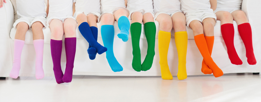 eine Reihe Kinderfüße, die alle bunte Socken tragen